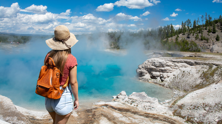 A hiker enjoys a view of a geyser in Yellowstone.