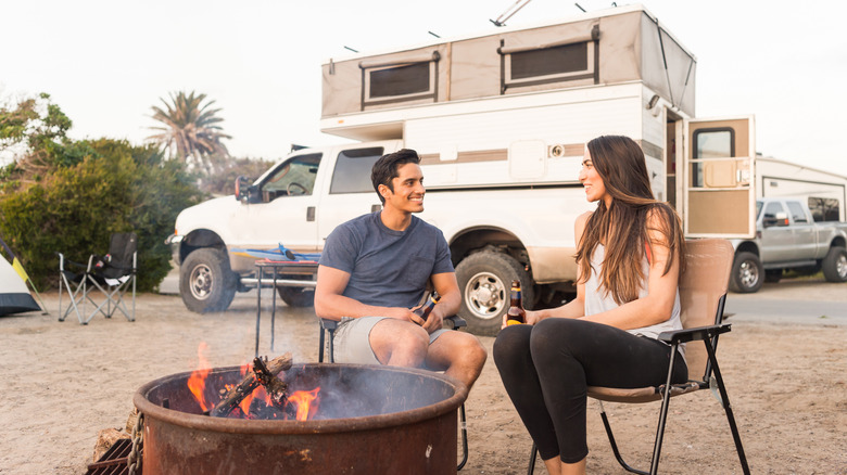 Couple sitting by campfire near RV site