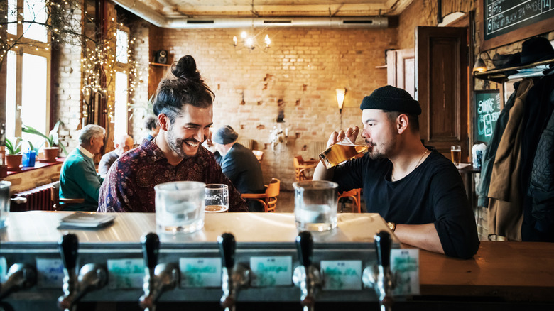 Two friends hanging out and drinking in a stylish bar together