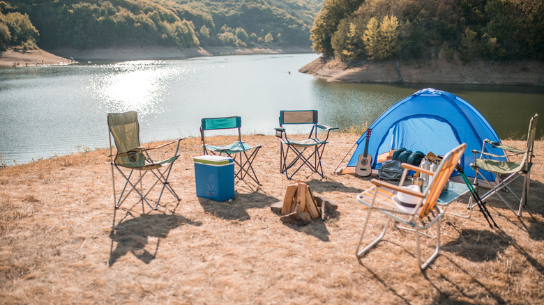 Camping tent, folding chairs and firewood lakeside camping setup