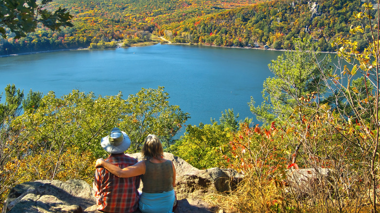 two people embracing while sitting overlooking a lake