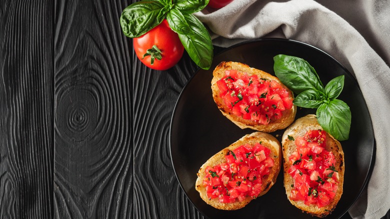 delicious Italian bruschetta with tomatoes on a black wooden rustic background