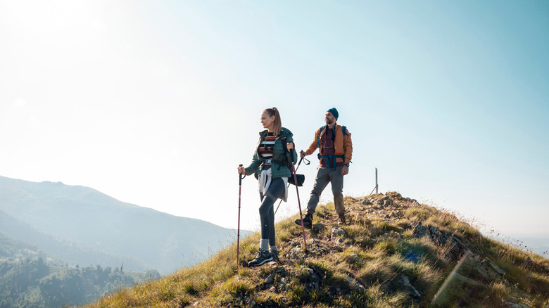 a couple hiking on a ridge with backpacks and trekking poles