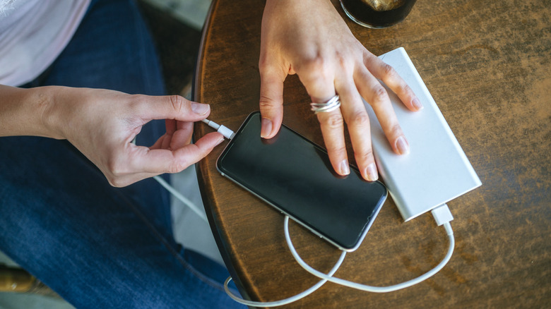 a person hands plugging mobile phone into a power bank