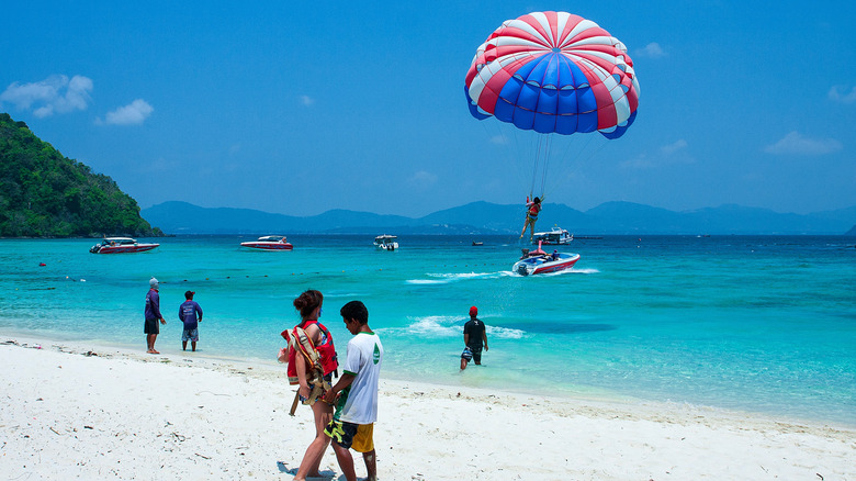 A tropical beach scene with someone parasailing