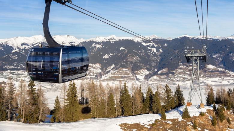 a gondola traveling over a snowy mountainside and ski slopes