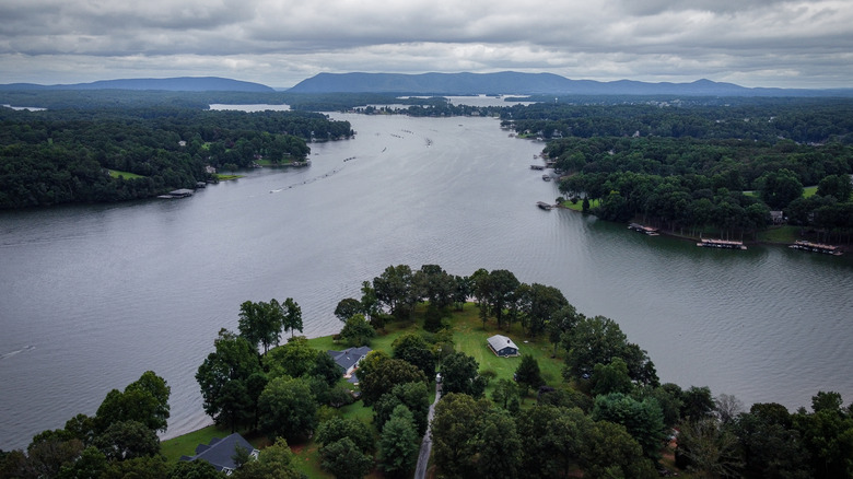 A sprawling lake surrounded by woodlands with a mountainous backdrop