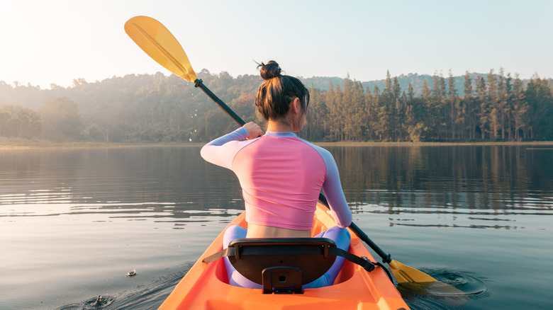 A woman canoeing on a tree-lined lake