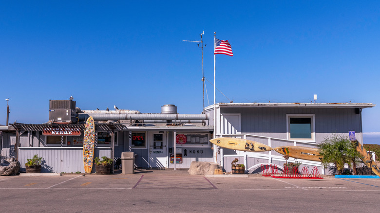A wooden oceanside store with decorative surfboards and an American flag.