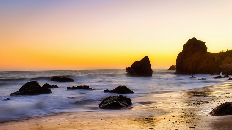 The waves come in at sunset over a beautiful beach in Malibu