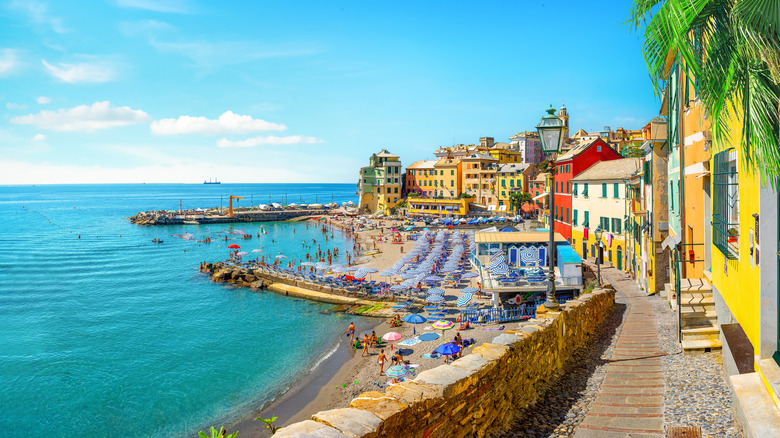 A panoramic sunny small beach in Bogliasco, Italy with the sea on one side and a coastal village on the other