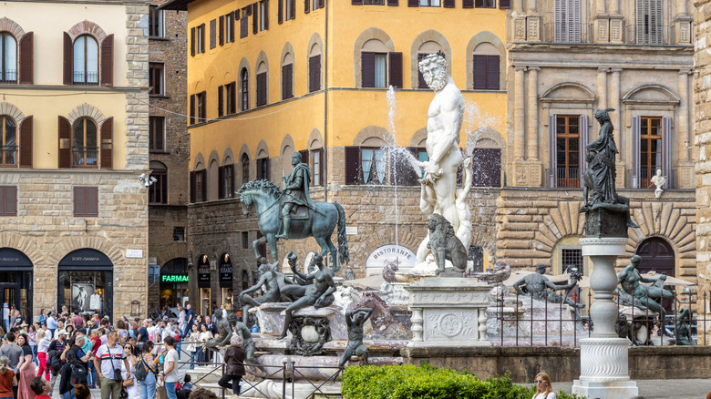 tourists flock around the Fountain of Neptune in front of the Palazzo Vecchio in Florence Italy