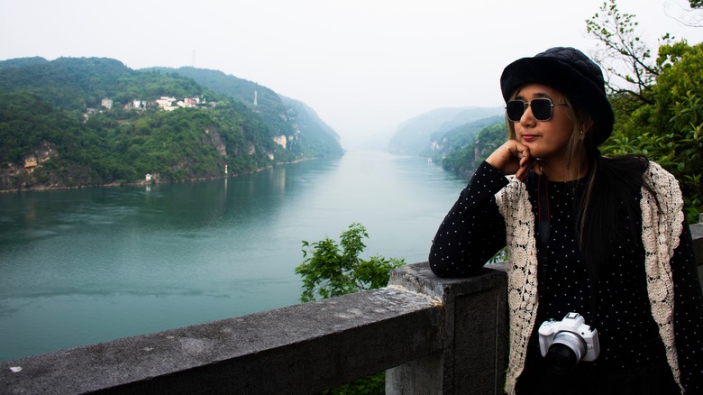 A traveler poses on the edge of a wall next to the Yangtze River, China