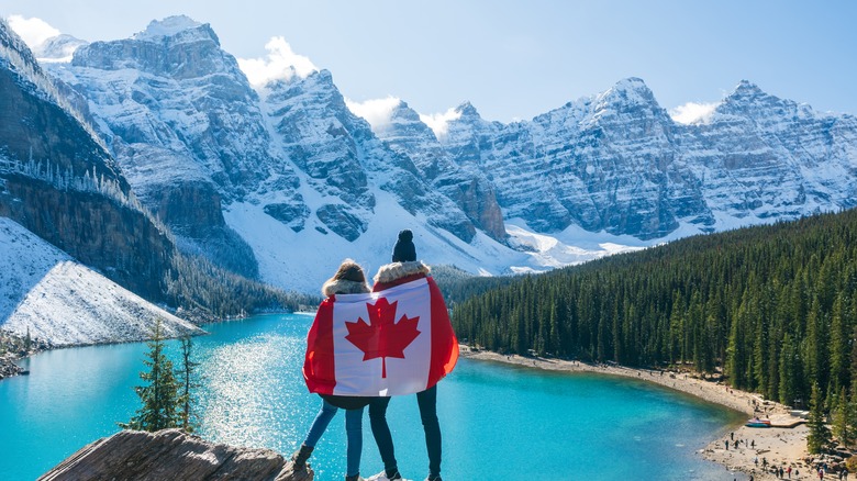 people wrapped canada flag while viewing the beautiful banff national park