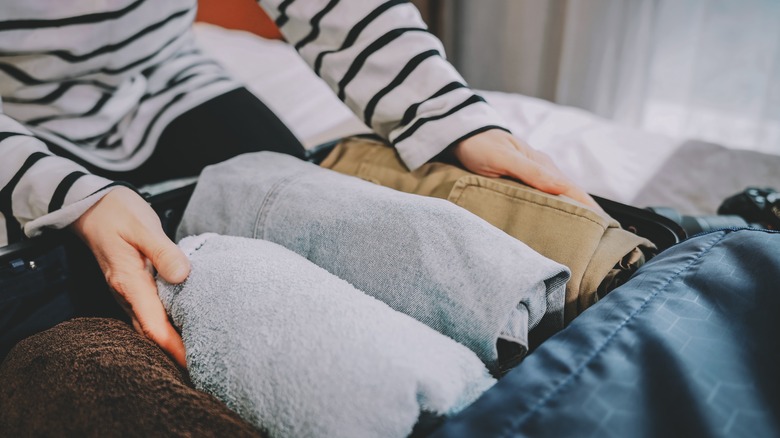 a person packing clothes in the bag