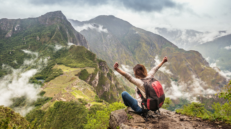 woman sitting on cliff with backpack at Machu Picchu