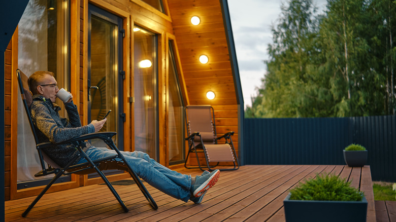 Man sipping from a mug on a cabin porch
