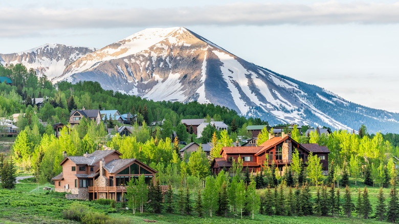 Houses in a green valley at the foot of snowy mountains