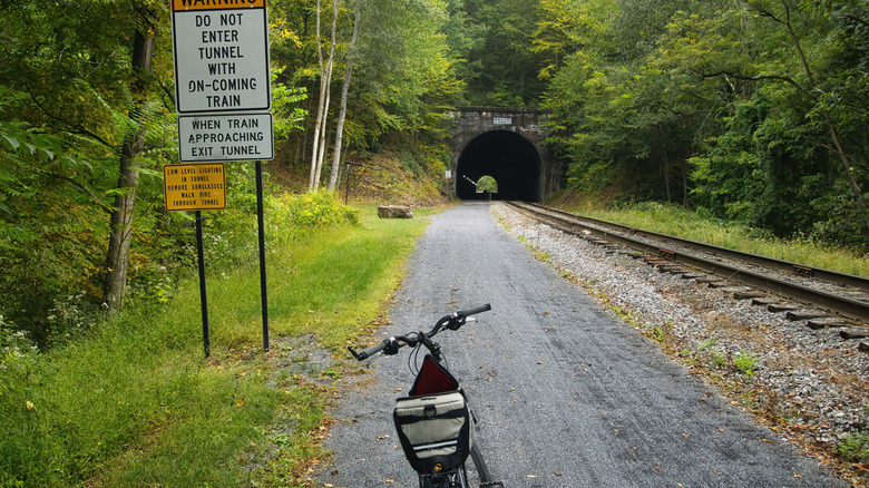 Bike parked near a warning sign at the approach to a tunnel on the Great Allegheny Passage recreational trail