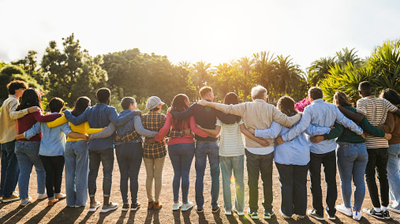 A line of people hugging with their backs to the viewer