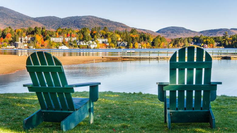 Adirondack chairs overlooking the water in Lake Placid, New York, and fall foliage-covered mountains in the background