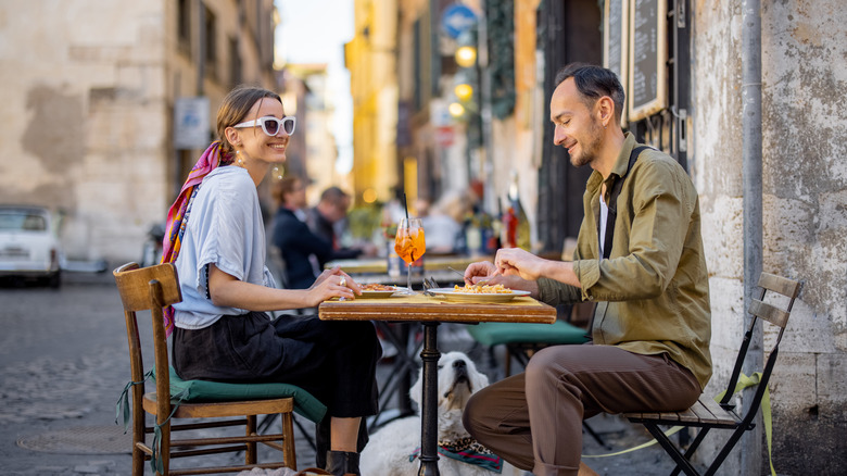 A man and woman eating outside at a restaurant in Italy