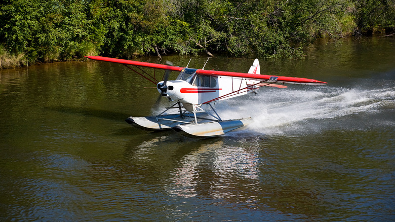 A small private float plane taking off in a wilderness setting.