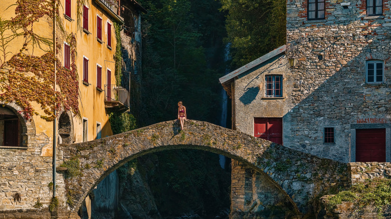 Person sitting on the medieval bridge in Nesso