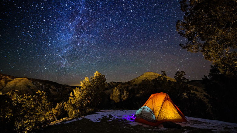 dimly lit ten at campsite during nighttime with starry sky