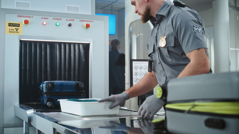 a security exmployee scanning a bag at the airport