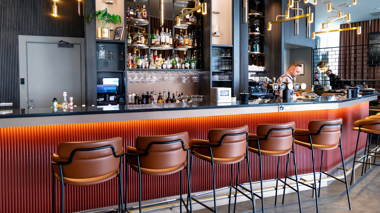 bar with stools, bottles, bartender