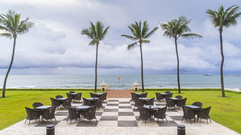 checkered seaside veranda with tables and palm trees
