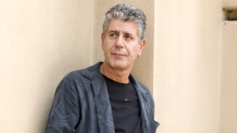 Anthony Bourdain leans against a wall