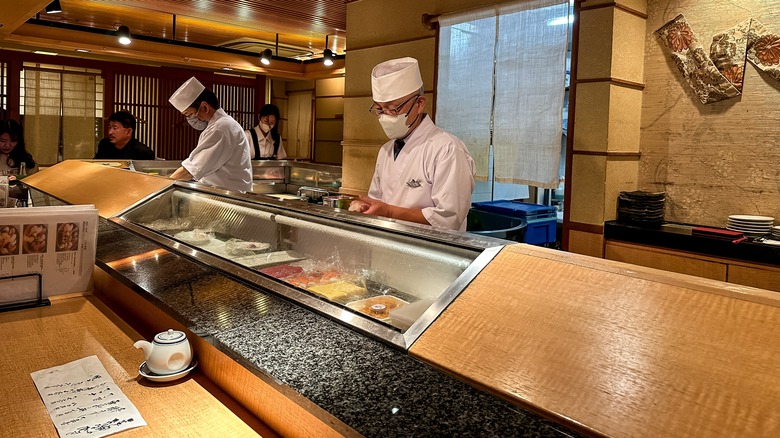 Sushi chefs preparing behind counter