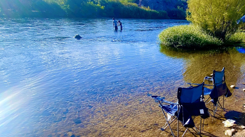 Pebble Beach Arizona two chairs in the water and two people crossing the Salt River