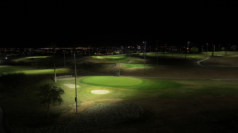 Golf greens at night lit with tall lights