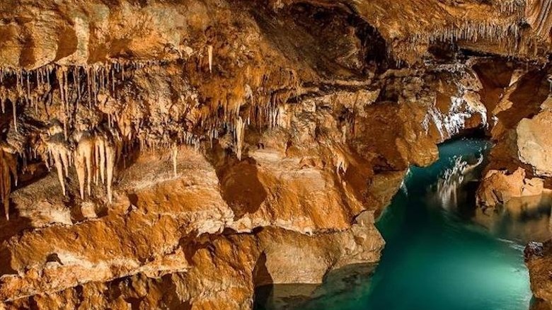 Cave wall and formations along a blue lake