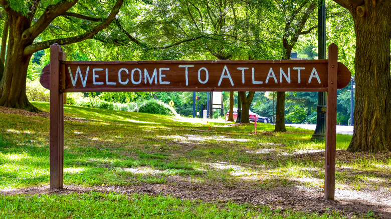 A wooden sign in a park with Welcome to Atlanta written on it