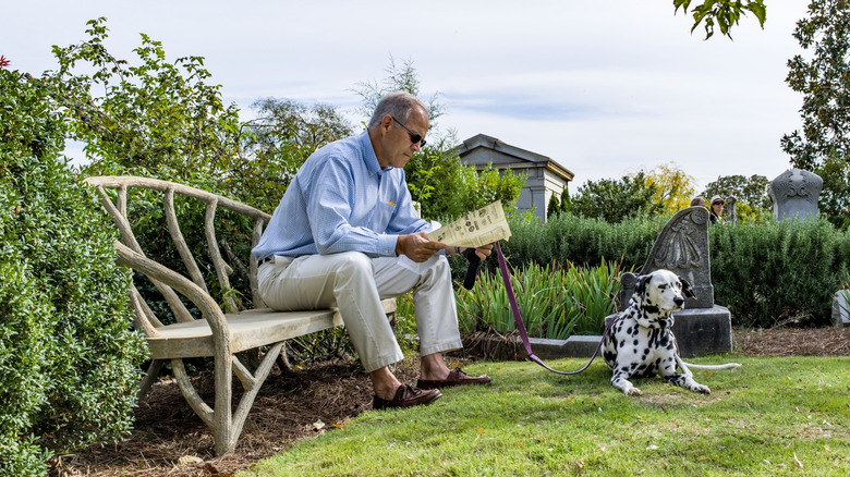 A man with his dog reading in Oakland Cemetery.