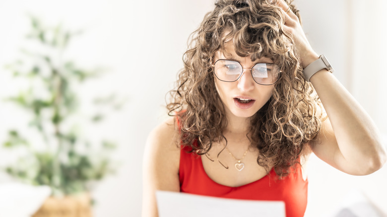 Young woman looking shocked at piece of paper