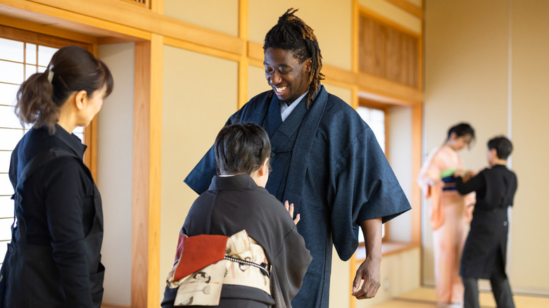 a man gets dressed in a japanese kimono in a dressing room