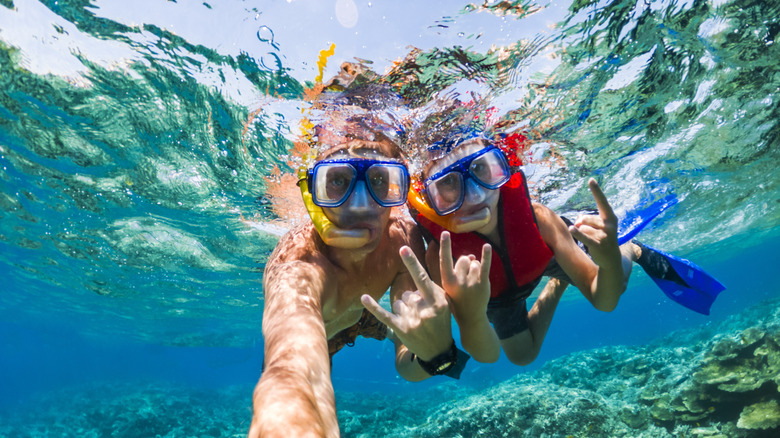 Two people snorkeling and waving to the camera