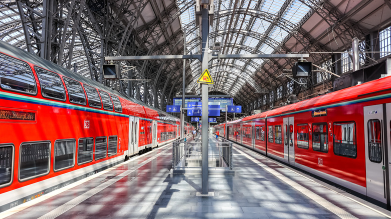 Two red trains in a modern glass train station.