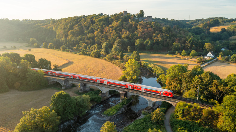 A train crosses a river in a rural landscape in Germany.