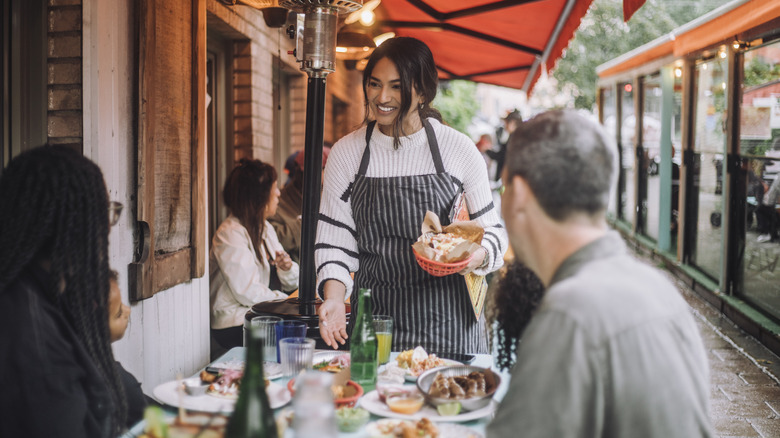 Restaurant server speaking to guests at a patio table