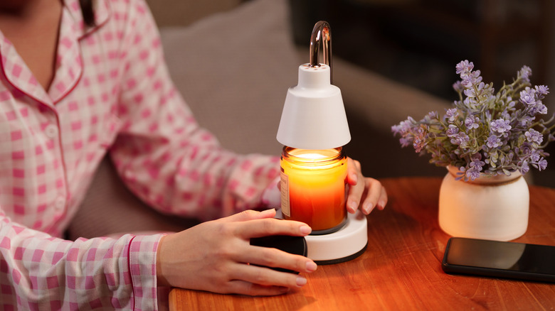 A woman in pajamas uses a candle warmer