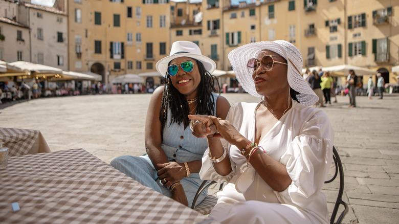 Two stylish women at a table in Italy.