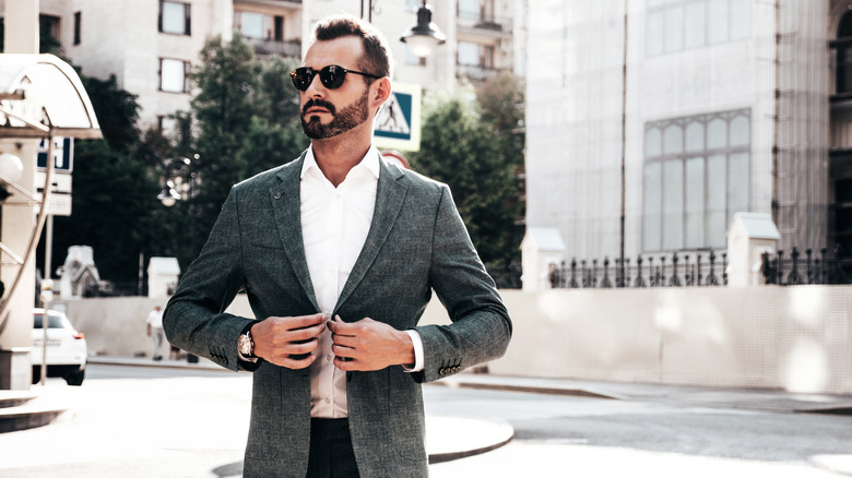A man buttons his blazer in a European street