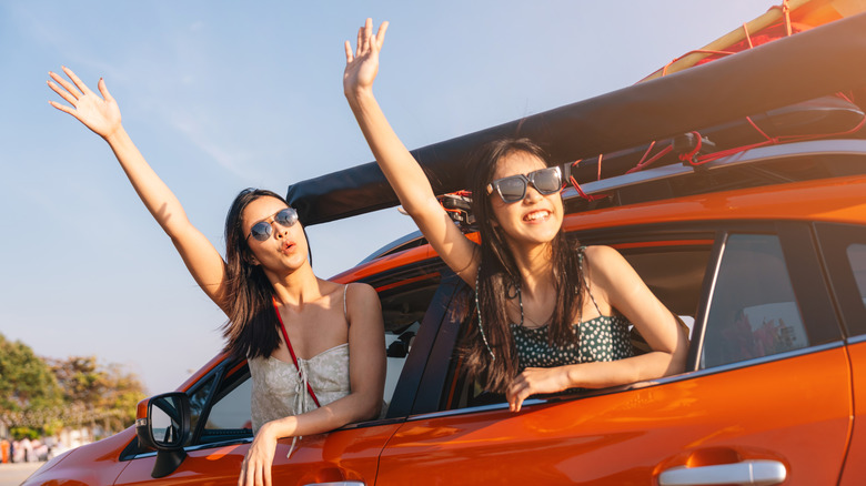 girls with heads and arms out car window