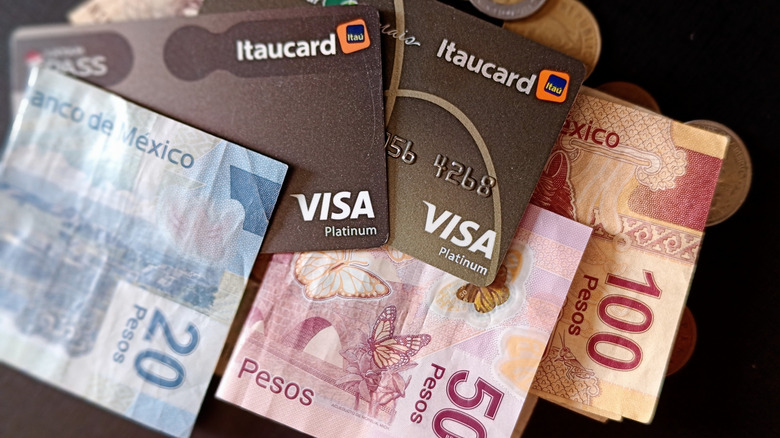 Mexican pesos and Visa credit cards on table